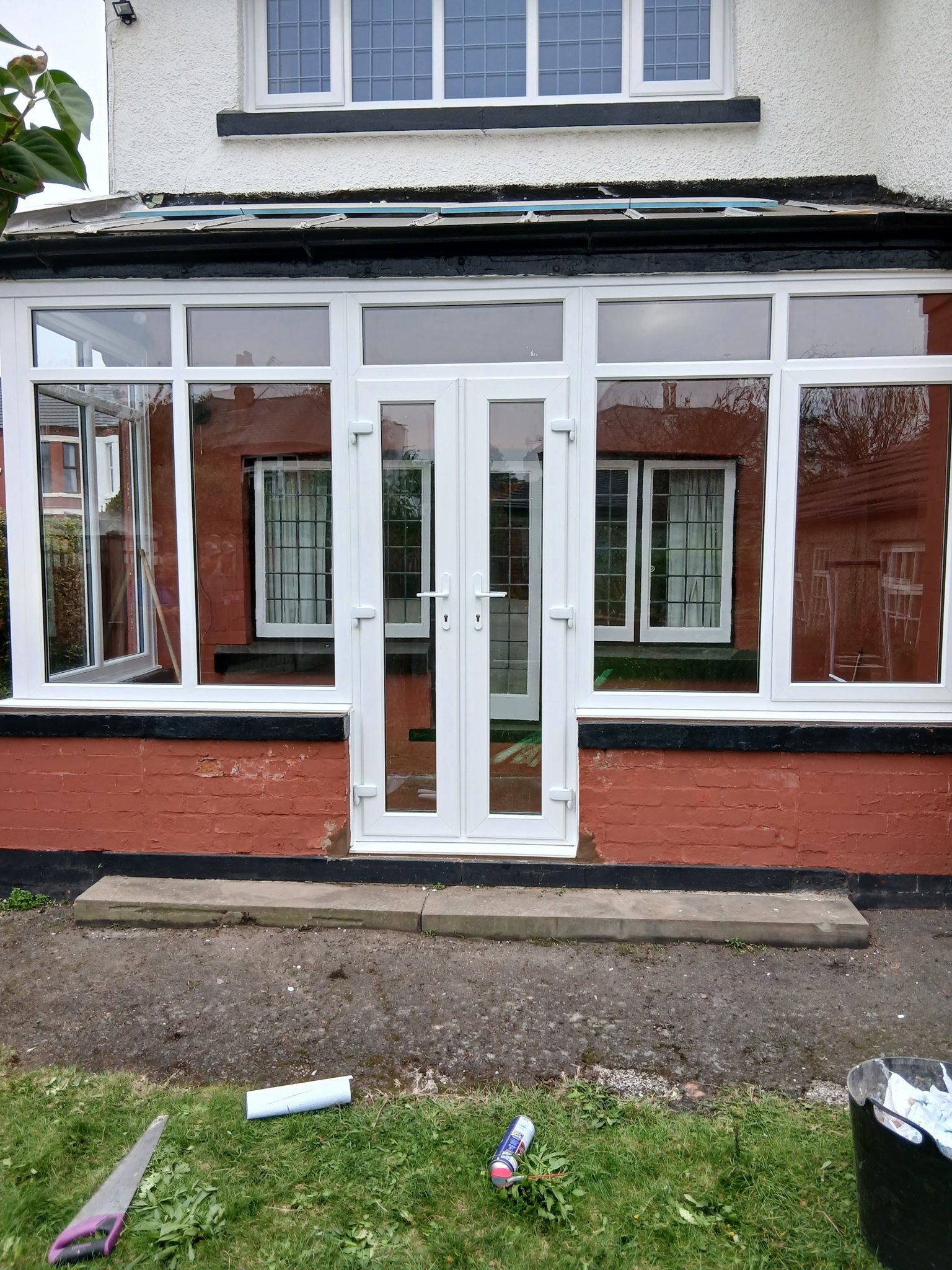 A white glazed porch with French doors across the front of a house